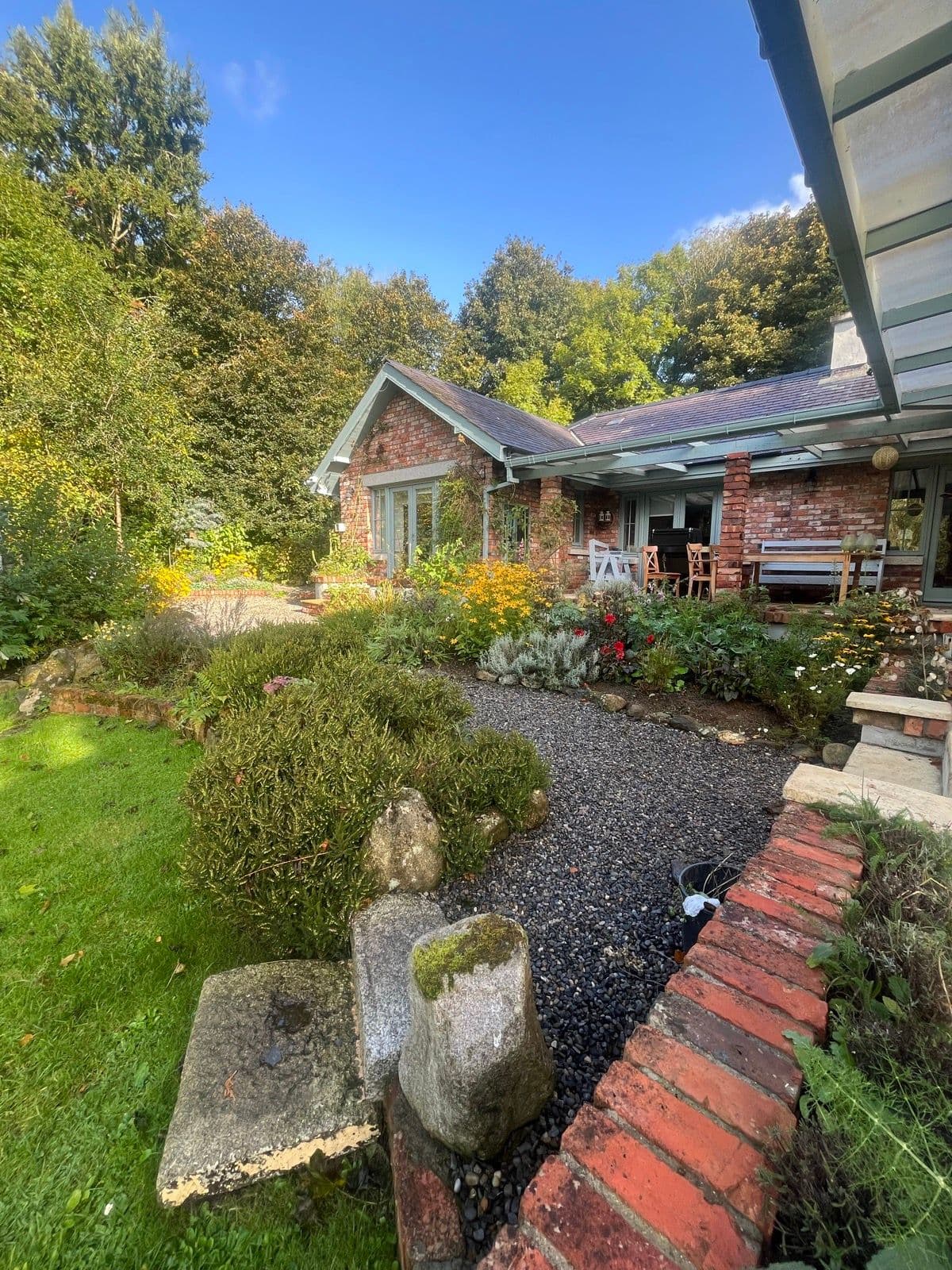 A cottage garden with a gravel path, black-pebble border and brick edging, Ireland