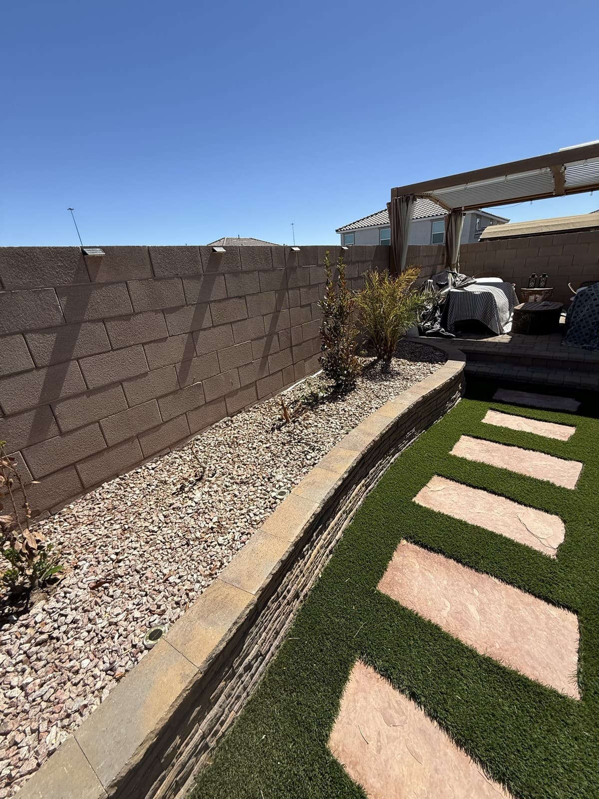 A desert gravel bed freshly planted along a backyard turf and stepping-stone path, Las Vegas