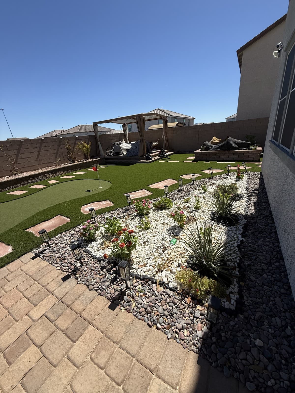 A newly planted flower and gravel bed beside a backyard putting green and turf lawn, Las Vegas